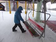 De stoel wordt bij het instappen met een bezem van sneeuw vrijgeveegd.