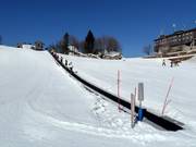 Oefenpiste met transportband bij het bergstation van de kabelbaan